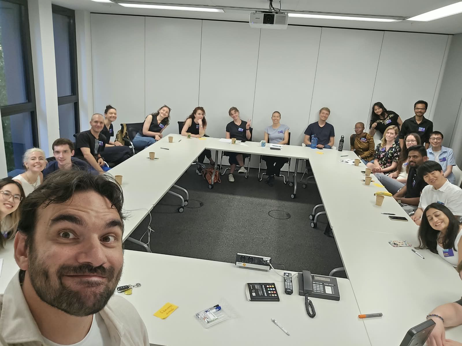Una sala con una ventina di ricercatori attorno a un tavolo lungo, durante un workshop